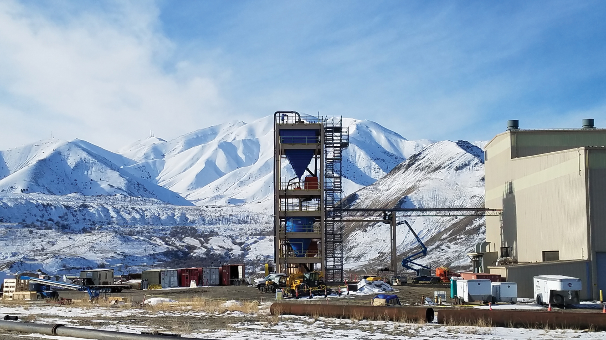 Outside view of an industrial building with snow covered mountains in the background